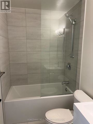 Brantford condo for rent - A white toilet sits next to a glass shower stall.