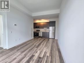 Pickering (Bay Ridges) condo for rent - A spacious room with wood flooring and a kitchen area in the background.