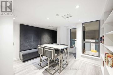 Toronto (Clanton Park) condo for rent - A modern dining room with a dark grey sofa and a glass display cabinet.