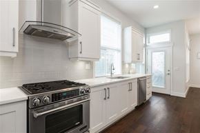 Surrey apartment for rent - A modern kitchen with white cabinets and a black stove top.