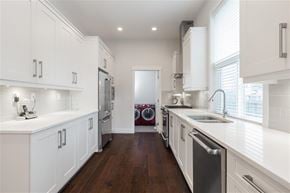 Surrey apartment for rent - A modern kitchen with white cabinets and a dark wood floor.