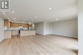 Toronto (Downsview-Roding-Cfb) multi-family for rent - A spacious room with wooden flooring and a kitchen area with a sink, stove, and cabinets.