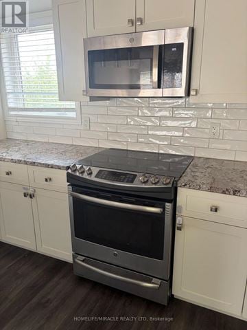 St. Catharines (Secord Woods) townhouse for rent - A modern kitchen with a stove top oven and microwave above it.