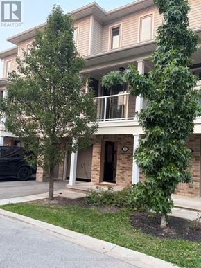 St. Catharines (Secord Woods) townhouse for rent - A tree in front of a building with a car parked in the background.