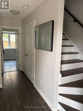 St. Catharines (Secord Woods) townhouse for rent - A hallway with a staircase and a mirror on the wall.