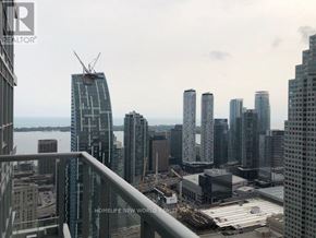 Toronto (Church-Yonge Corridor) condo for rent - A cityscape with a view of a body of water and a crane in the distance.