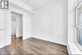 Burnaby apartment for rent - A room with wooden floors and white walls, with a doorway leading to another room.