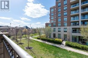Oakville (Jc Joshua Creek) townhouse for rent - A view of a residential area with a tall building and a well-maintained lawn.