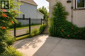 Hamilton apartment for rent - A black metal fence separates a sidewalk from a green bush.