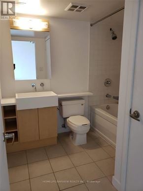 Toronto (Waterfront Communities) condo for rent - A white toilet is in a bathroom with a white sink and a white bathtub.