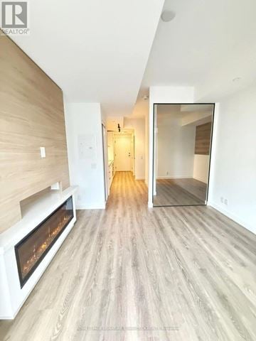 Toronto (Greenwood-Coxwell) condo for rent - A modern living room with a fireplace and a mirror on the wall.