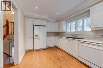 Oakville apartment for rent - A well-lit, spacious kitchen with white cabinets and wooden flooring.