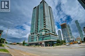 Mississauga condo for rent - A tall glass building stands in the foreground of a city street.