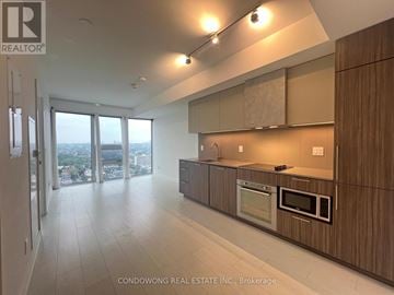 Toronto (Waterfront Communities) condo for rent - A modern kitchen with wooden cabinets and a microwave.