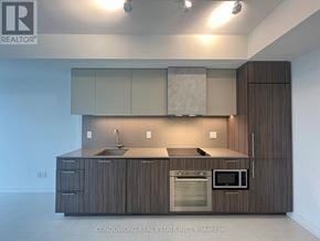 Toronto (Waterfront Communities) condo for rent - A modern kitchen with dark wood cabinets and stainless steel appliances.