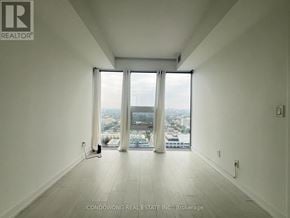 Toronto (Waterfront Communities) condo for rent - A large, empty room with a view of the city through the windows.