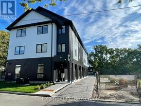 Barrie (Wellington) condo for rent - A modern two-story building with a black and white exterior and a sign that reads "Wellness Community" in front of it.