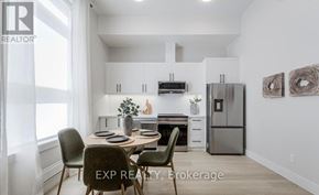 Barrie (Wellington) condo for rent - A dining area with a table set for four and a kitchen in the background.
