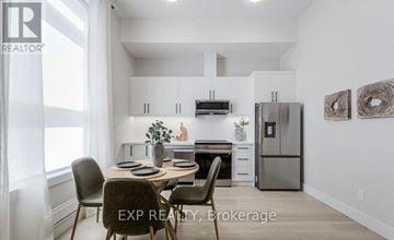 Barrie (Wellington) condo for rent - A dining area with a table set for four and a kitchen in the background.