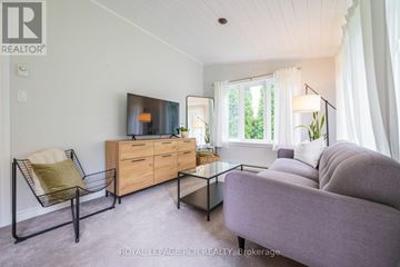 Orangeville apartment for rent - A living room with a grey couch, a wooden dresser, and a chair with a green cushion.