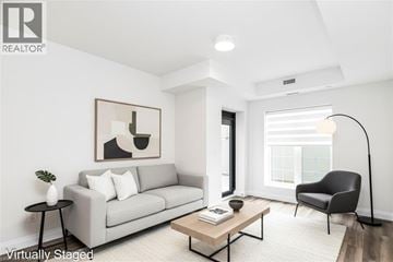 Ancaster condo for rent - A living room with a grey couch, a black chair, a wooden coffee table, and a painting on the wall.
