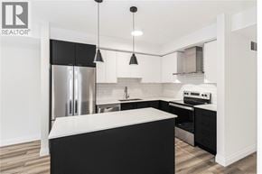 Ancaster condo for rent - A modern kitchen with black and white cabinetry and stainless steel appliances.