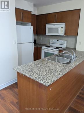 Mississauga (City Centre) condo for rent - A kitchen with a granite counter top and a white fridge.