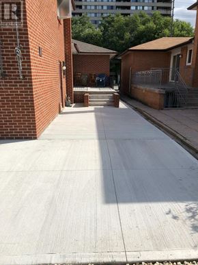 Toronto (Kingsview Village-The Westway) apartment for rent - A long concrete walkway leads to a brick building with a sign that says "Real Estate.".