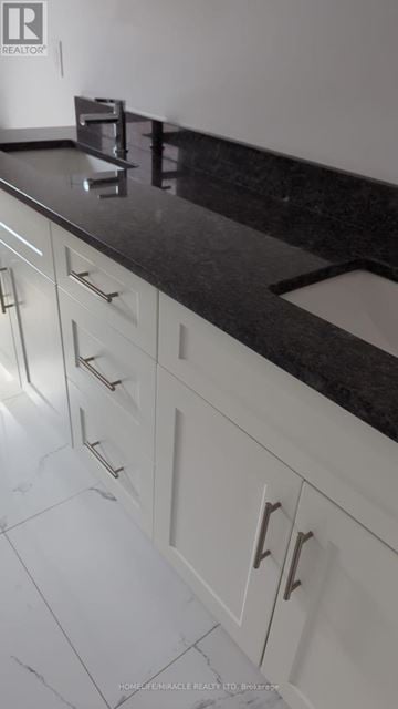 Amherstburg apartment for rent - A kitchen with white cabinets and a black counter top.