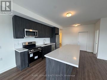 Clarington (Bowmanville) condo for rent - A kitchen with black cabinets and stainless steel appliances.