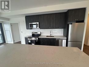 Clarington (Bowmanville) condo for rent - A kitchen with black cabinets and stainless steel appliances.