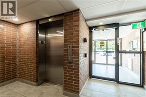 Guelph condo for rent - A hallway with a brick wall and a metal elevator.