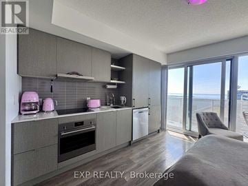 Toronto (Waterfront Communities) condo for rent - A kitchen with grey cabinets and a large window overlooking the ocean.
