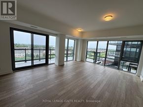 Clarington (Bowmanville) condo for rent - A spacious room with wooden flooring and large windows overlooking a cityscape.