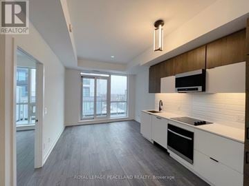 Richmond Hill (South Richvale) condo for rent - A modern kitchen with white cabinets and a wooden accent wall.