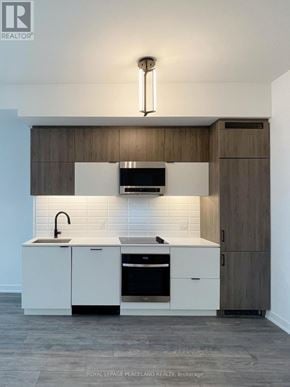 Richmond Hill (South Richvale) condo for rent - A modern kitchen with white cabinets and a wooden backsplash.