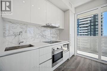 Vaughan (Vaughan Corporate Centre) condo for rent - A modern kitchen with white cabinets and a marble backsplash.