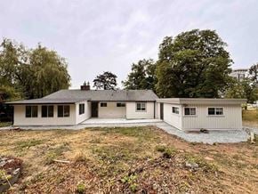 Langley apartment for rent - A house with a grey roof and white walls is surrounded by trees and grass.