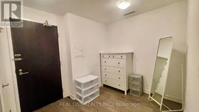 Toronto (Kensington-Chinatown) condo for rent - A bedroom with a white dresser and a black door.