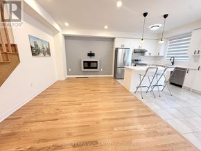 Pickering townhouse for rent - A spacious kitchen and living room with wooden flooring and white walls.