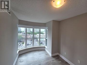 Toronto (Willowdale West) condo for rent - A real estate brokerage image of an empty room with a view of a parking lot and buildings outside.