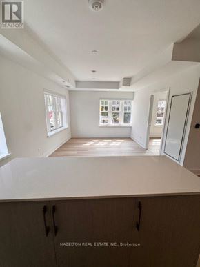 Toronto (Yonge-Eglinton) condo for rent - A real estate listing photo of a white kitchen with wood floors and cabinets.