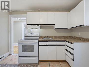 London apartment for rent - A kitchen with white cabinets and a stove top oven.