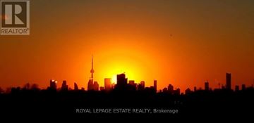 Toronto (East End-Danforth) condo for rent - A city skyline at sunset with the sun partially obscured by buildings.