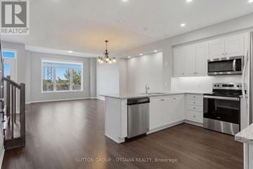 Ottawa townhouse for rent - A modern kitchen with white cabinets and stainless steel appliances.