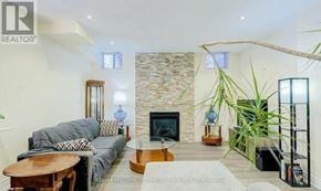 Vaughan (Patterson) apartment for rent - A living room with a stone fireplace and a grey couch.