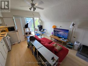 Toronto (High Park-Swansea) multi-family for rent - A living room with a red couch and a flat screen TV.