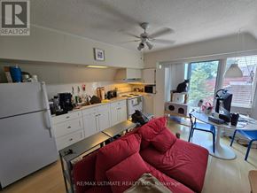 Toronto (High Park-Swansea) multi-family for rent - A kitchen with a refrigerator, a dining table, and a couch.