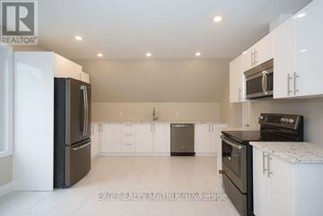 Ottawa duplex for rent - A kitchen with white cabinets and black appliances.