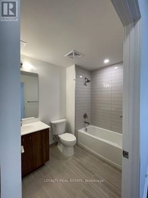 Kitchener condo for rent - A white toilet sits in a bathroom with a white bathtub.